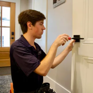 CrewPros employee changing a door handle.